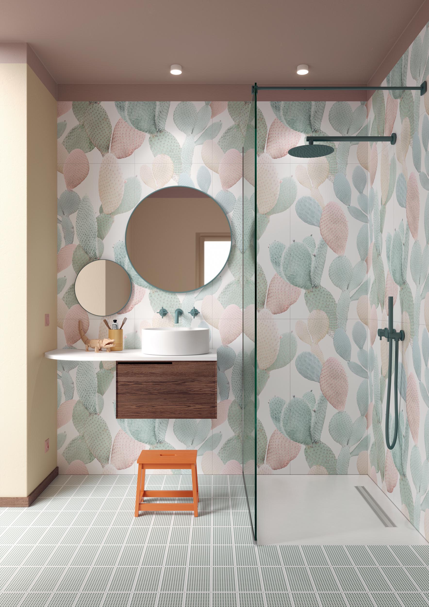 Jasna łazienka ze ścianą wyłożoną płytkami we wzór pastelowych kaktusów, z kabiną prysznicową, wiszącą szafką z blatem z umywalką, dwoma lustrami