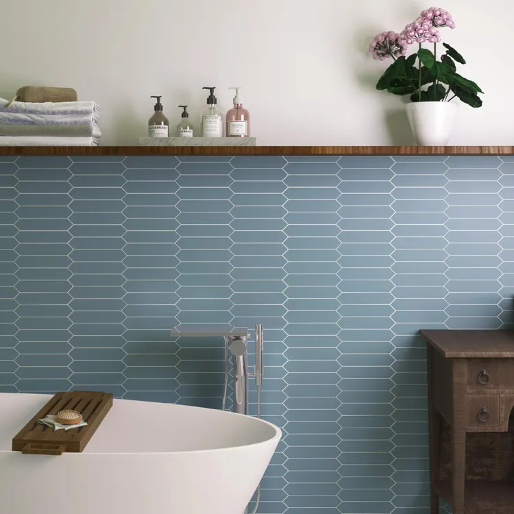 Ściana w łazience wyłożona w części niebieskimi płytkami w kształcie strzały z wanną i wiszącą półką
