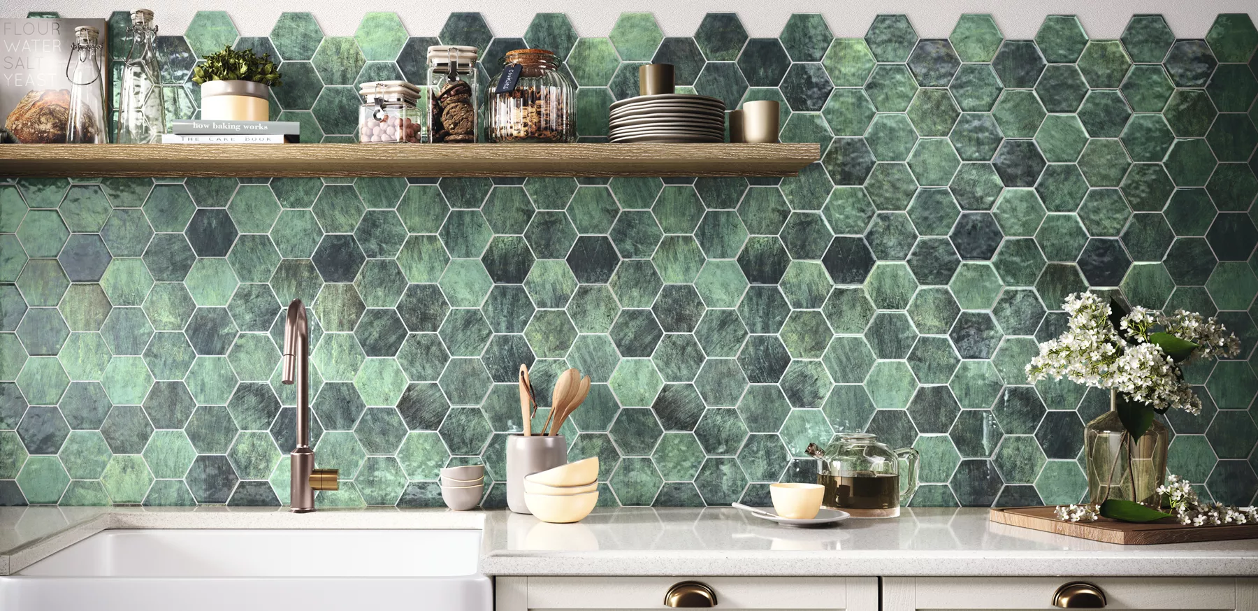 Ściana w kuchni wyłożona zielonymi płytkami w kształcie heksagonu z jasnymi meblami, wiszącą półką drewnianą, naczyniami i kwiatami w wazonie
