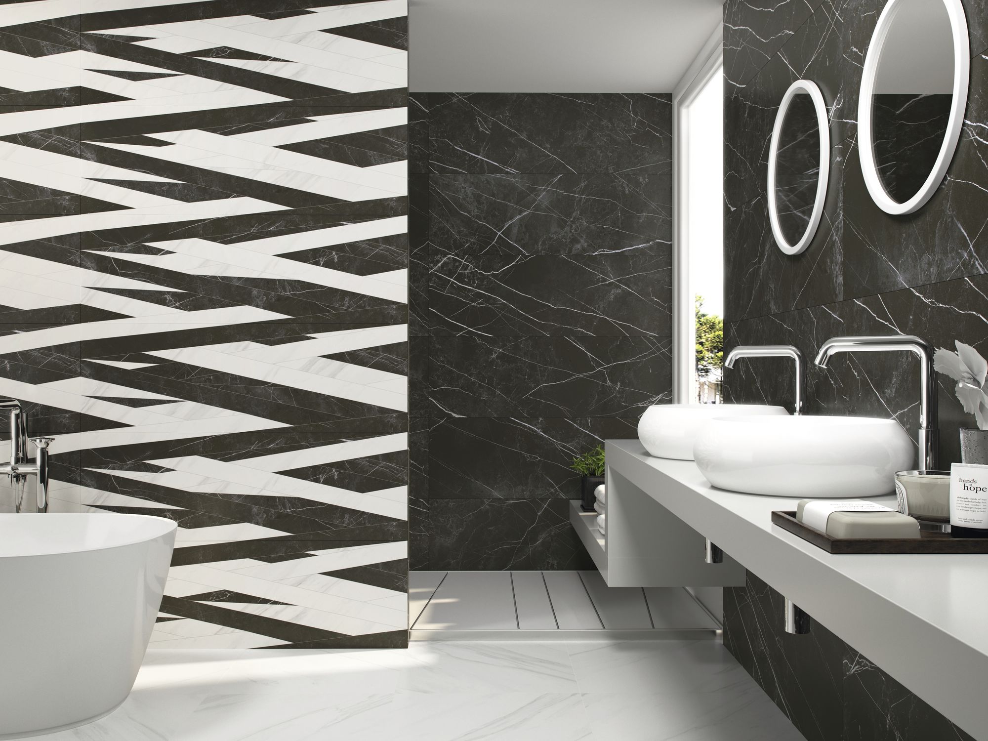 Łazienka wyłożona jasnymi i ciemnymi płytkami imitującymi marmur, z prysznicem we wnęce, białą wanną wolnostojącą oraz blatem z dwiema umywalkami nablatowymi i dwoma okrągłymi lustrami