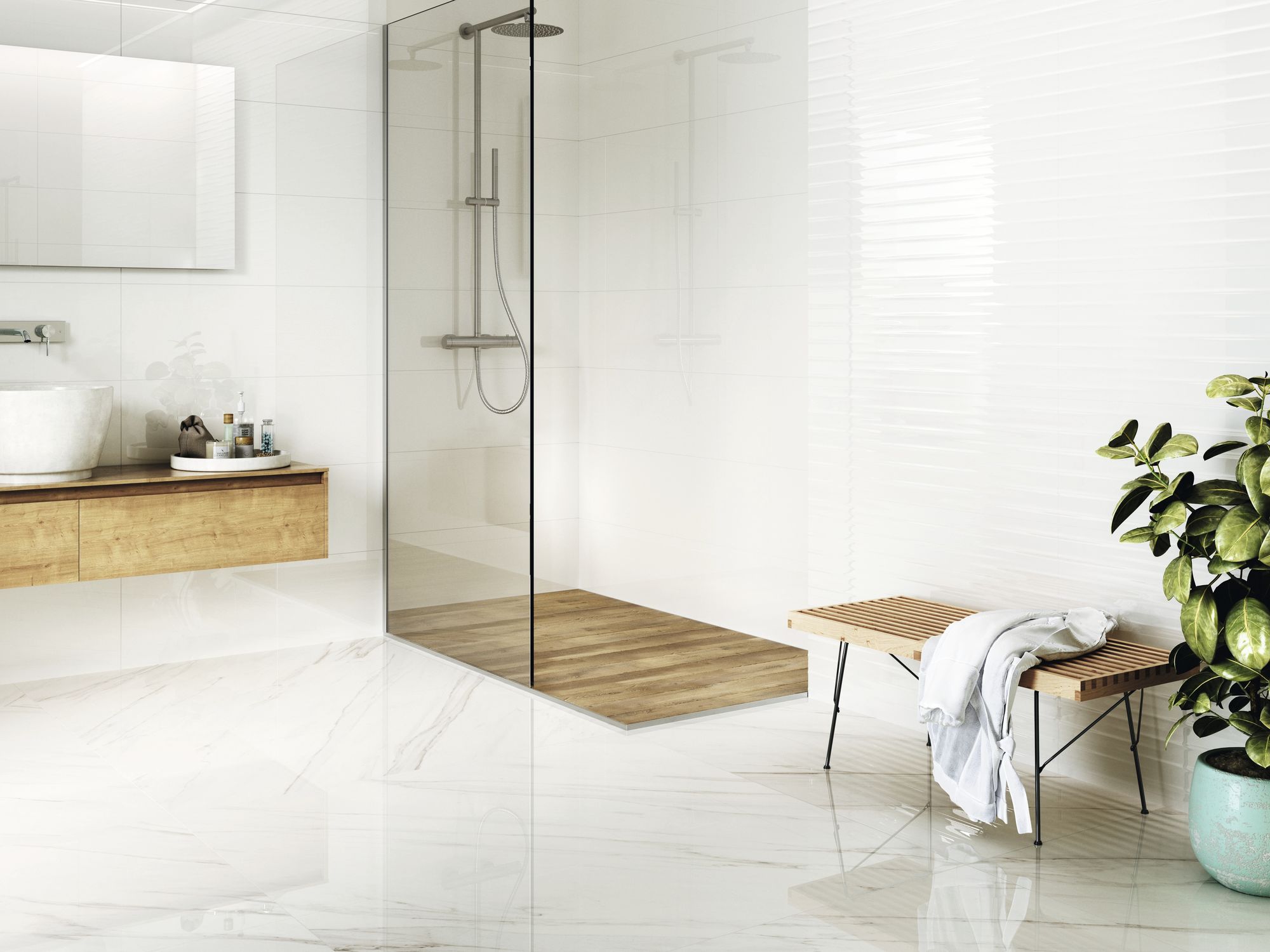 Jasna łazienka wyłożona białymi płytkami w połysku z kabiną prysznicową, drewnianą szafką wiszącą z dużą, białą umywlaką i prostokątnym lustrem, drewnianą ławeczką z białym szlafrokiem i dużym kwiatem w donicy