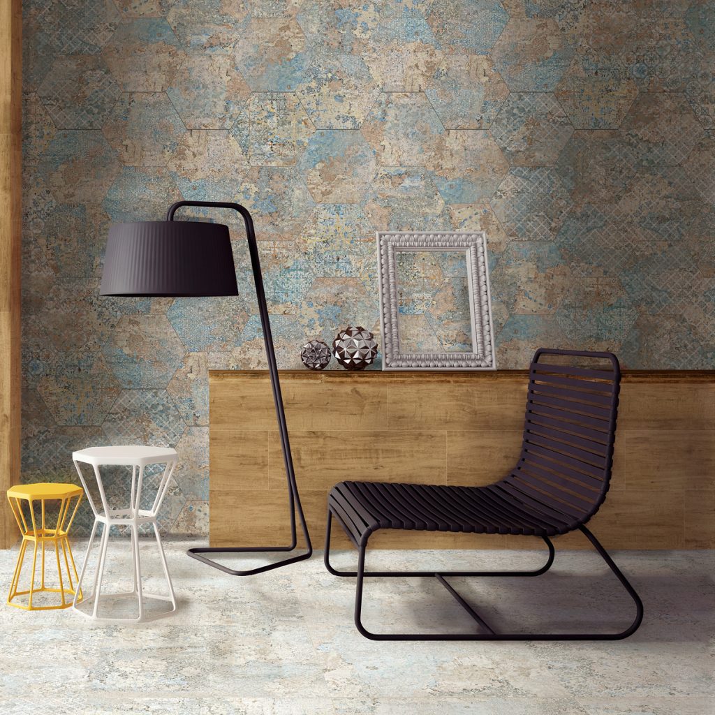 Pokój wyłożony dekoracyjnymi płytkami imitującymi stary dywan z kolekcji Carpet z długą szafką drewnianą, lampą stojącą, czarnym krzesłem oraz białym i żółtym taboretem