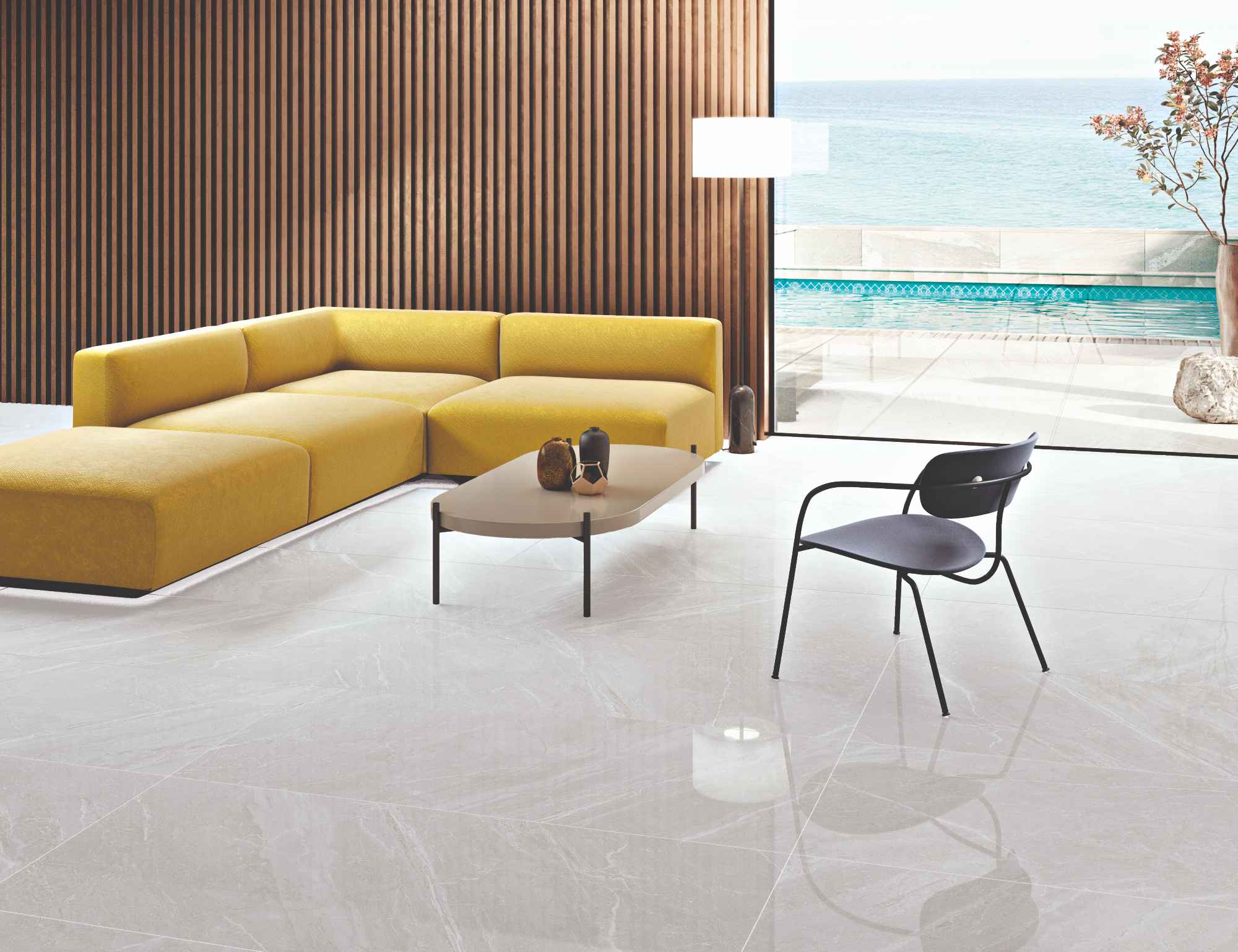 Salon z podłogą wyłożoną jasnymi płytkami imitującymi kamień w połysku z kolekcji Mainstone z żółtą kanapą, czarnym krzesłem i stolikiem