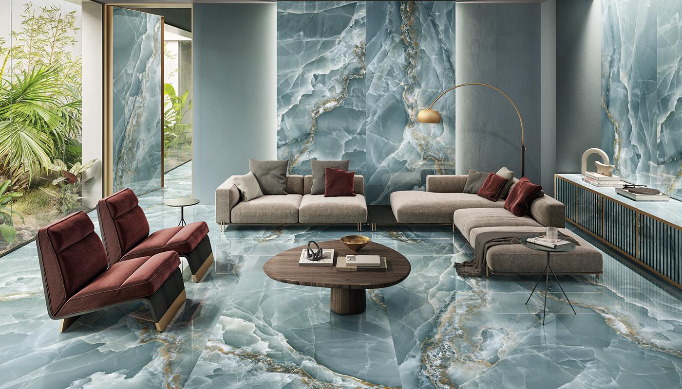 Elegancki salon wyłożony zielonymi płytkami imitującymi kamień onyks, z beżową kanapą, dwoma fotelami, drewnianym stolikiem, szafką, lampą stojącą