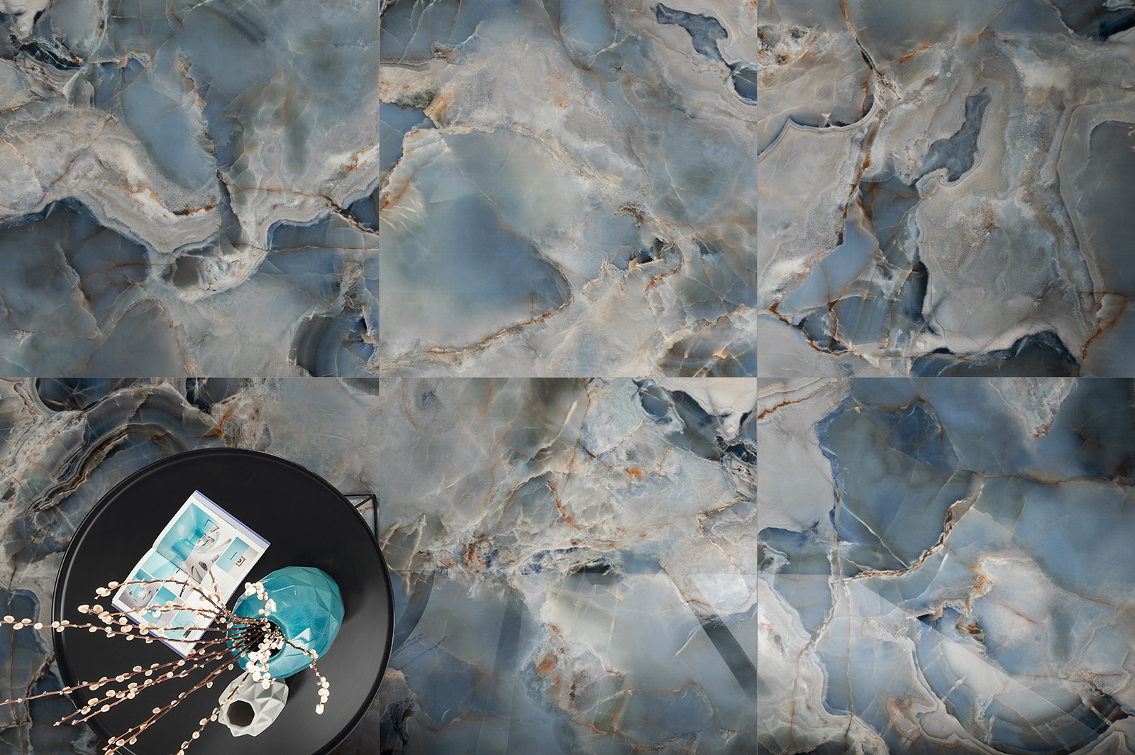 Widok z góry na podłogę wyłożoną niebieskimi płytkami imitującymi kamień szlachetny z czarnym, okrągłym stolikiem z wazonem i czasopismem
