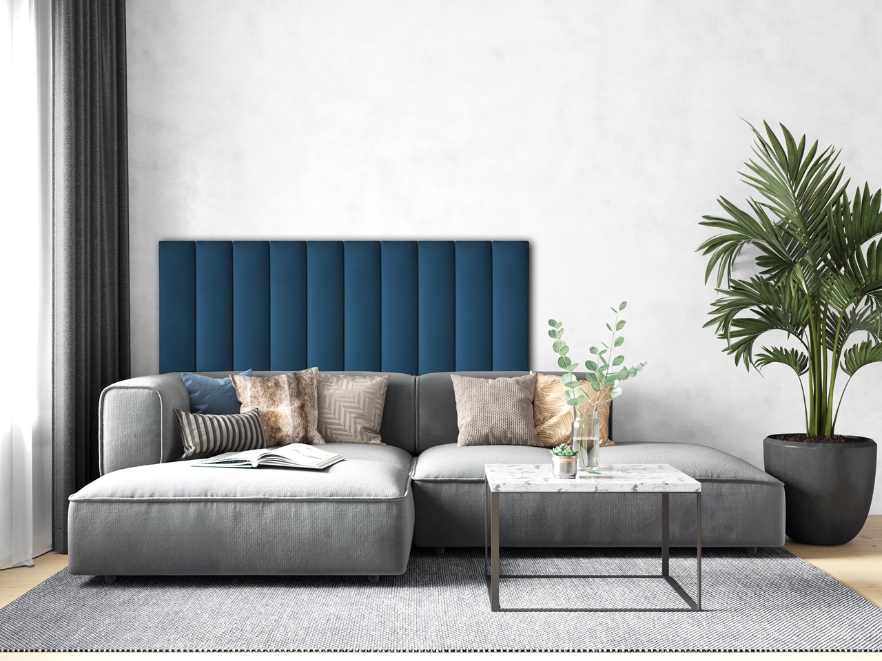Salon z szarą kanapą i dywanem i częścią ściany za kanapą wyłożoną niebieskimi panelami tapicerowanymi