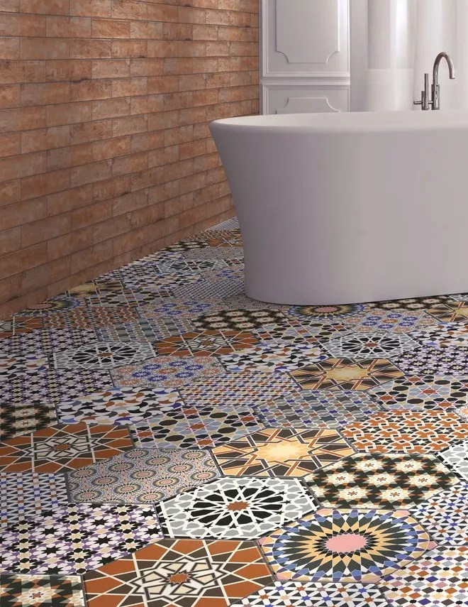 Podłoga w łazience wyłożona kolorowymi płytkami patchwork w kształcie heksagonu z białą wanną wolnostojącą i ceglaną ścianą