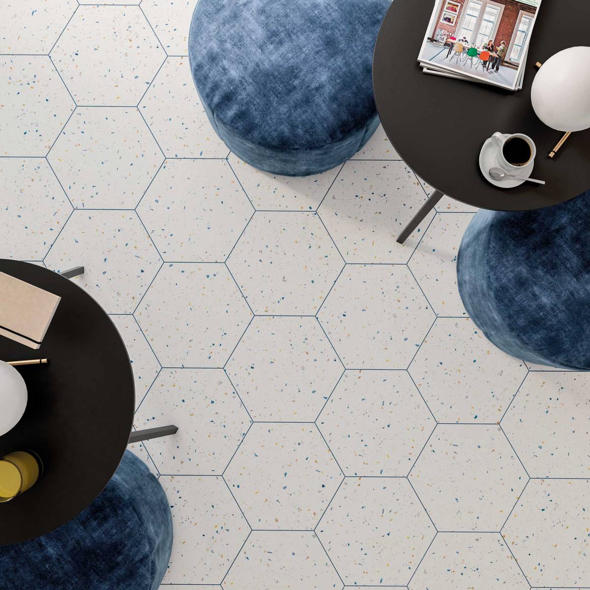 Widok z góry na podłogę wyłożoną płytkami heksagonalnymi lastryko, z okrągłymi stolikami i niebieskimi pufami