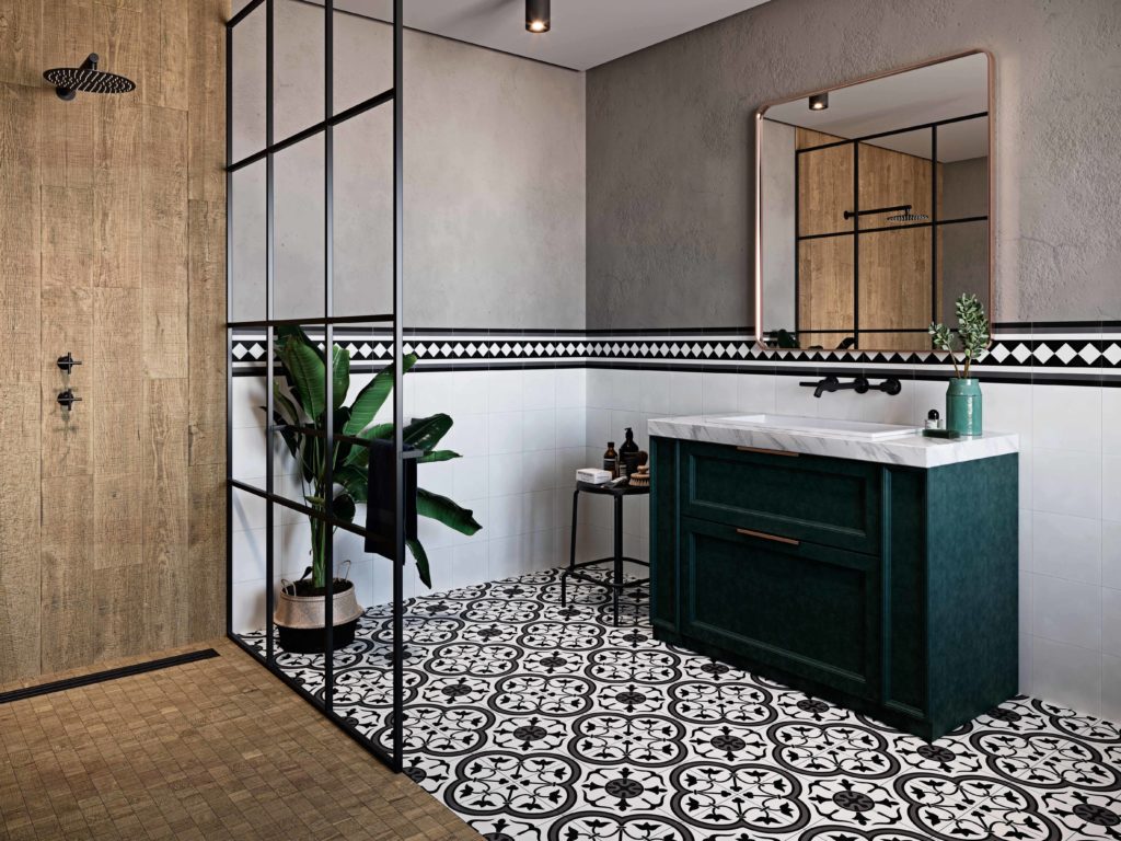 Łazienka z podłogą wyłożoną biało-czarnymi płytkami patchworkowymi i kabiną prysznicową wyłożoną drewnem, z zieloną szafką z umywalką, lustrem i dużym kwiatem w donicy