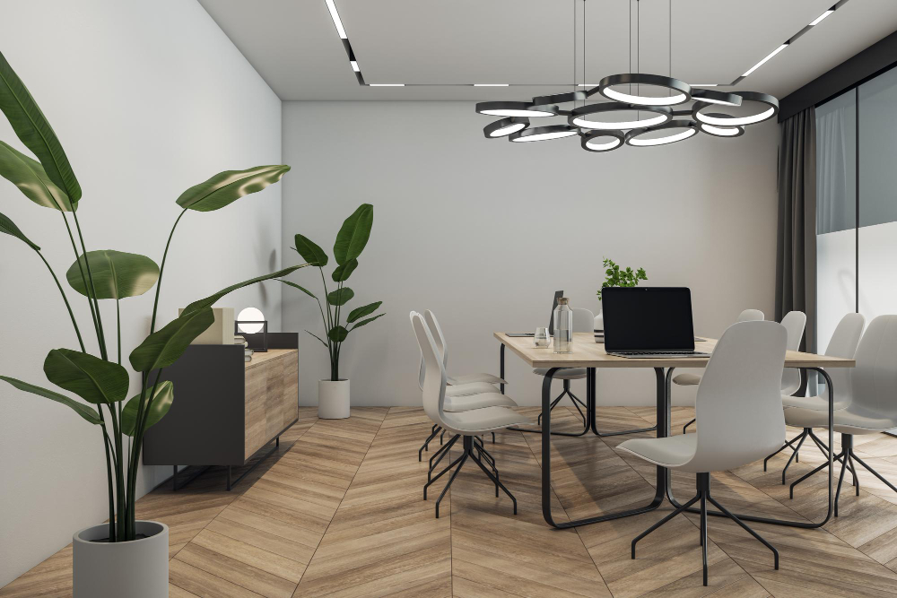 Biuro z drewnianą jodełką na podłodze, stołem na środku z białymi krzesłami, lampą wiszącą, komodą i roślinami
