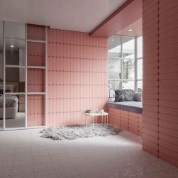 Stylowa sypialnia ze ścianami wyłożonymi różowymi cegiełkami Grace O Blush Matt z wnęką przy oknie z poduszką, dywanem i małym stolikiem oraz łóżkiem za drzwiami