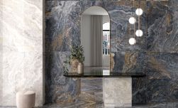 Elegancki korytarz z czarną, wiszącą półka z wazonem, podłużnym lustrem, lampą wiszącą i płytkami imitującymi marmur na ścianie z kolekcji Linz