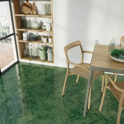 Podłoga w jadalni wyłożona zielonymi cegiełkami w połysku Bejmat Olive Gloss, z drewnianym stołem i krzesłami oraz półkami z naczyniami