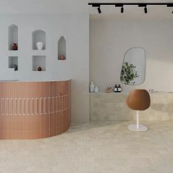 Salon kosmetyczny z recepcją wyłożoną pomarańczowymi cegiełkami w połysku Aquarelle Toffee z półkami w ścianie z wazonami, fotelem przed lustrem i kosmetykami