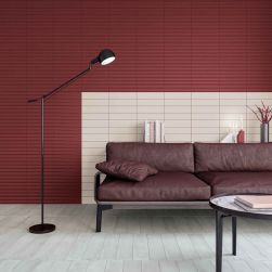 Salon ze ścianą w części wyłożoną czerwonymi cegiełkami 3D Stripes Transition Garnet Matt z bordową kanapą i lampą stojącą