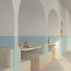 Restauracja z łukami i ścianami wyłożonymi w połowie białymi cegiełkami ściennymi Casbah Talc Matt, z jasnymi kanapami i marmurowymi stolikami