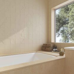 Ściana w łazience wyłożona beżowymi cegiełkami ze wzorem Casbah Decor Mix Sand Matt z oknem i zabudowaną wanną