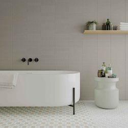 Łazienka ze ścianą wyłożoną szarymi cegiełkami bazowymi Texiture Grey Matt, z białą wanną, wiszącą półeczką i stolikiem z kosmetykami
