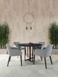 Pok&oacute;j z drewnopodobnymi płytkami w jodełkę Chevron A Wood Light na ścianie i z szarą podłogą, z czarnym okrągłym stolikiem i szarymi krzesłami oraz lampą wiszącą
