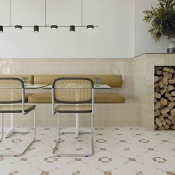 Restauracja z patchworkową podłogą i ścianą w połowie wyłożoną beżowymi cegiełkami w połysku Fayenza Square Greige Gloss, z białymi stołami, krzesłami i lampą wiszącą
