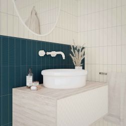 Biała łazienka z częścią ściany wyłożoną niebieskimi cegiełkami dekoracyjnymi Texiture Pattern Mix Ocean Matt, z szafką wiszącą z umywalką nablatową, białą baterią podtynkową i okrągłym lustrem