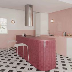 Kolorowa kuchnia z jedną ścianą wyłożoną różowymi cegiełkami Grace Blush Gloss, z białymi i różowymi meblami, wyspą i dwoma białymi taboretami