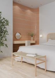 Sypialnia w stylu skandynawskim z fragmentem ściany wyłożonym pomarańczowymi cegiełkami w połsyku Aquarelle O Toffee z drewnianą półką, krzesłem, okrągłym lustrem i białym łóżkiem