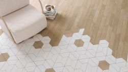 Widok na podłogę wyłożoną drewnopodobnymi płytkami w kształcie jodełki Chevron A Wood Mid z białymi płytkami trapezowymi oraz jasnym fotelem