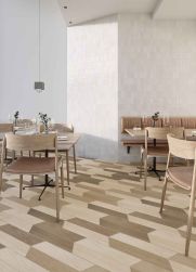 Restauracja z ciemnymi płytkami drewnopodobnymi w jodełkę Chevron B Wood Dark na podłodze i białymi ścianami, drewnianymi stolikami i krzesłami, ławą wiszącą i lampą