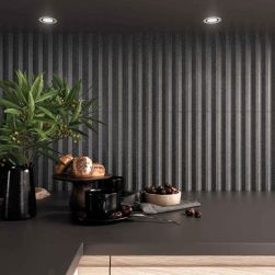 Ściana w kuchni między meblami wyłożona grafitowymi cegiełkami 3D z efektem kamienia Stripes Graphite Stone Matt z czarnym blatem z naczyniami
