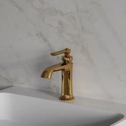 Widok z boku na złotą baterię umywalkową Omnires Armance stojącą na białej umywalce na tle jasnej, marmurowej ściany
