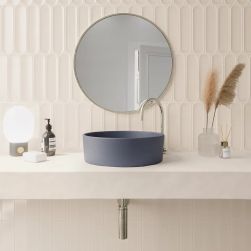 Ściana w łazience wyłożona kremowymi cegiełkami w połysku Aquarelle Vapor z wiszącym blatem z niebieską umywalką nablatową, okrągłym lustrem, lampką i akcesoriami