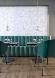 Restauracja z ciemnymi płytkami drewnopodobnymi w jodełkę Chevron B Wood Dark na podłodze, z kanapą i fotelami w kolorze butelkowej zieleni i lampami wiszącymi