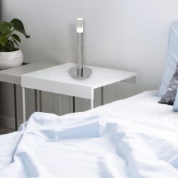 Stolik nocny w sypialni przy łóżku z lampką stojącą srebrną Ice