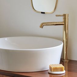 Widok na białą umywalkę nablatową okrągłą ze złotą baterią stojącą Omnires Y z mydłem