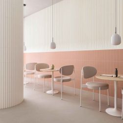 Restauracja z częścią ściany wyłożoną beżowymi cegiełkami 3D Stripes Transition Dove Matt, z okrąłymi stolikami, krzesełkami i lampami wiszącymi