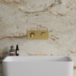 Widok od przodu na białą umywalkę ze złotą baterią podtynkową Omnires Contour na beżowej ścianie z kamienną powierzchnią