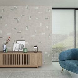 Salon ze ścianą wyłożoną szarymi płytkami rustykalnymi Pottery Square Grey, z niebieskim fotelem, dywanem i drewnianą szafką z ozdobami