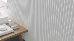 Widok na ścianę wyłożoną białymi cegiełkami 3D Stripes Ice White Matt z drewnianą szafką z umywalką i kosmetykami