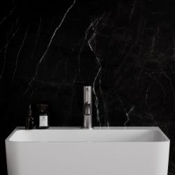 Widok od przodu na białą umywalkę z baterią stojącą w kolorze niklu Omnires Parma na tle czarnej ściany