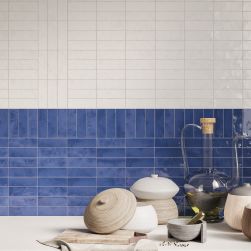 Ściana w kuchni wyłożona w części białymi cegiełkami w połysku Bejmat White Gloss oraz niebieskimi, z białym blatem z naczyniami