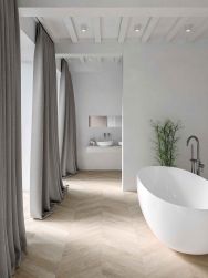 Długa łazienka z płytkami drewnopodobnymi w jodełkę Chevron A Wood Light, z białą wanną owalną, wiszącą półką z umywalką nablatową i lustrem