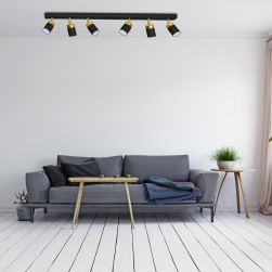 Biały pokój z panelami na podłodze, szarą kanapą, małym stolikiem i czarną lampą sufitową Joker Black/Gold