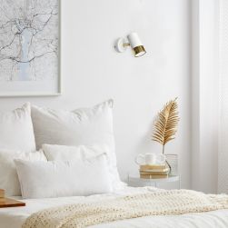 Sypialnia, łózko z białymi poduszkami, beżową narzutą, stolik nocny z ozdobami, obraz, na ścianie kinkiet Dani
