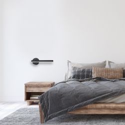 Sypialnia, łóżko z narzutą i poduszkami, stolik nocny, szary dywan na podłodze, na ścianie kinkiet Sydney