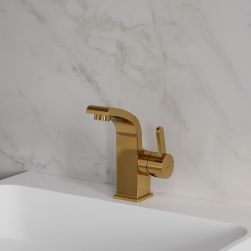 Widok z boku na złotą baterię umywalkową Omnires Darling stojącą na białej umywalce na tle jasnej, marmurowej ściany