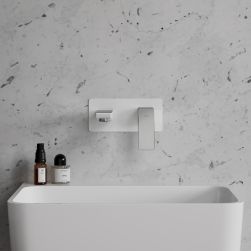 Widok na białą umywalkę oraz baterię podtynkową białą Omnires Parma na tle białej, marmurkowej ściany