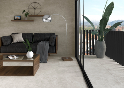 salon, duże drzwi tarasowe, ciemna kanapa, roślina na tarasie, stolik kawowy, lampa, na podłodze i na ścianie płytki grain stone sand