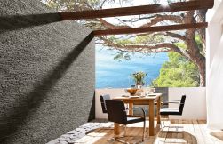 Taras z widokiem na ocean z zastawionym drewnianym stolikiem, trzema fotelami i kamieniem dekoracyjnym Link Stone Graphite
