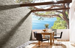 Taras z widokiem na ocean z zastawionym drewnianym stolikiem, trzema fotelami i kamieniem dekoracyjnym Link Stone Grigio